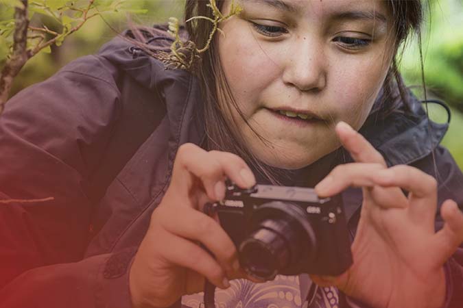 Young person taking a picture outside with a small digital camera