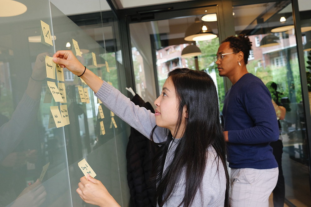 A young woman and man putting Post-it notes on a board
