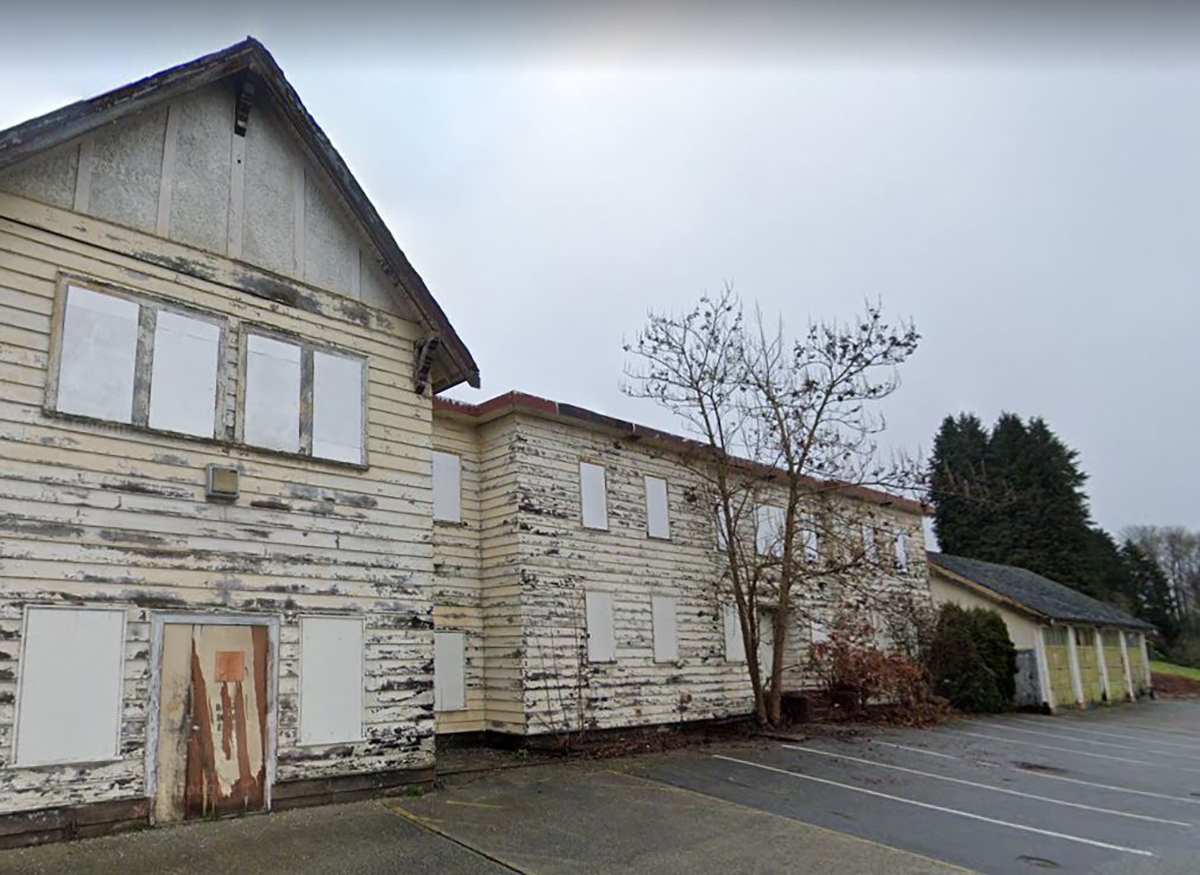 Old worn down, boarded up building with paint pealing off the siding.